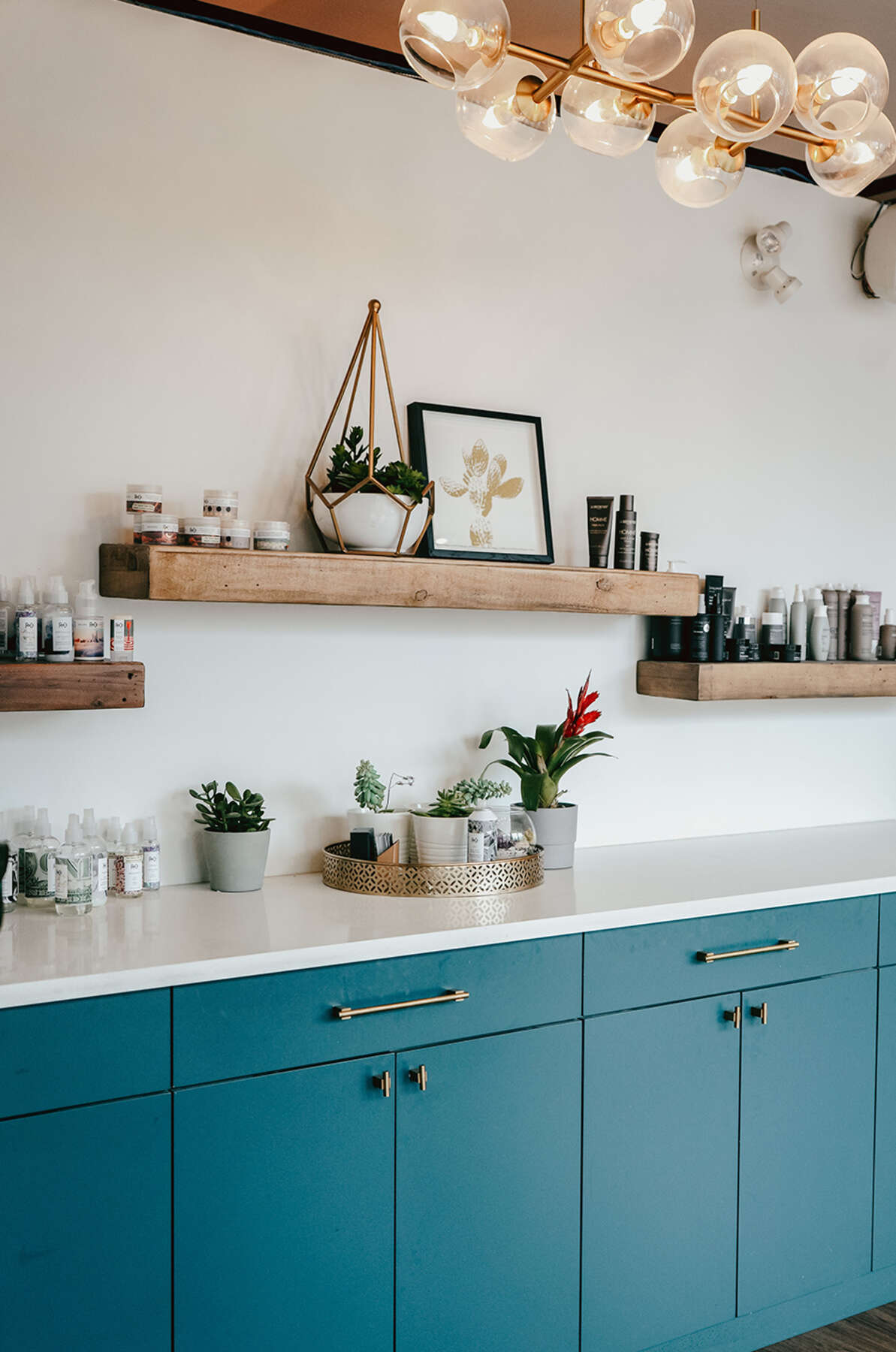 Office kitchenette with teal cabinets, open wood shelving and a globe light fixture